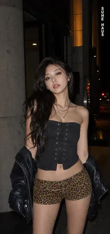 Nighttime direct-flash portrait of a stylish young woman standing outside a building.