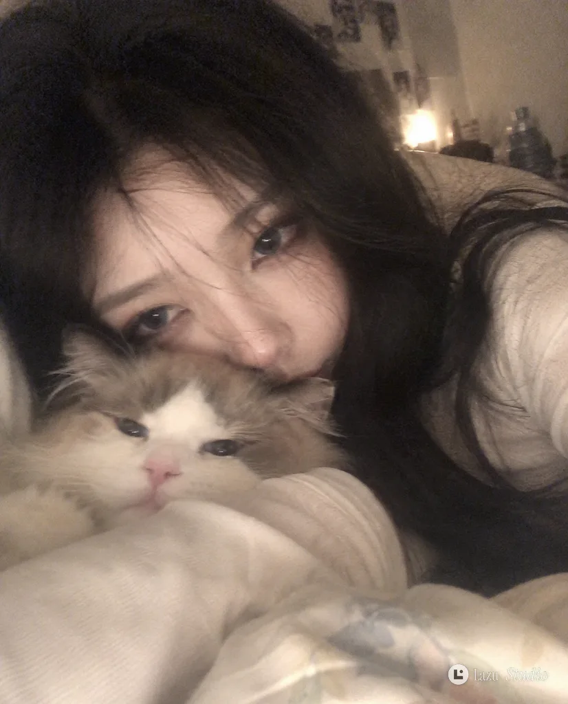 布団に横たわり猫を抱きながら、目元だけを見せている黒髪女性の接写スナップ。