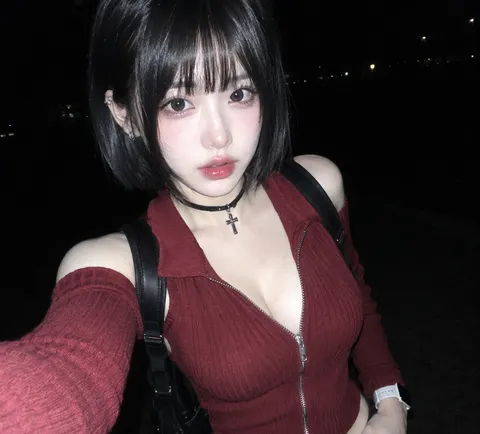Nighttime close-up flash photo of a woman with a black bob and bangs looking into the lens.
