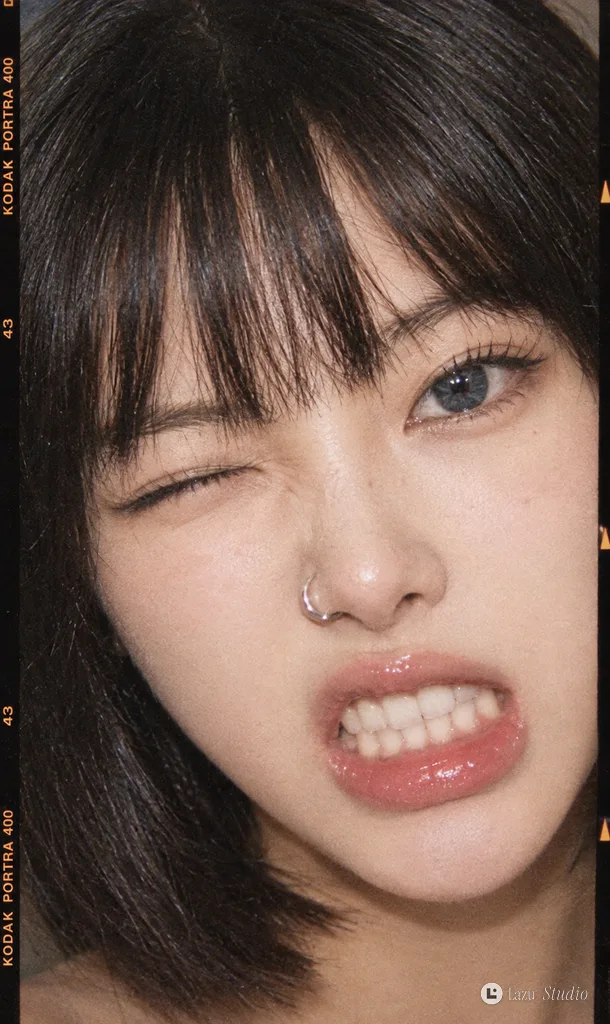 戴著鼻環的年輕女子眨眼並露出咬牙笑容的底片特寫。