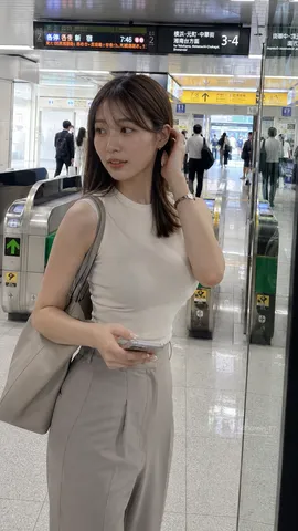 Candid photo of a young woman walking near the ticket gates of a train station in the morning.