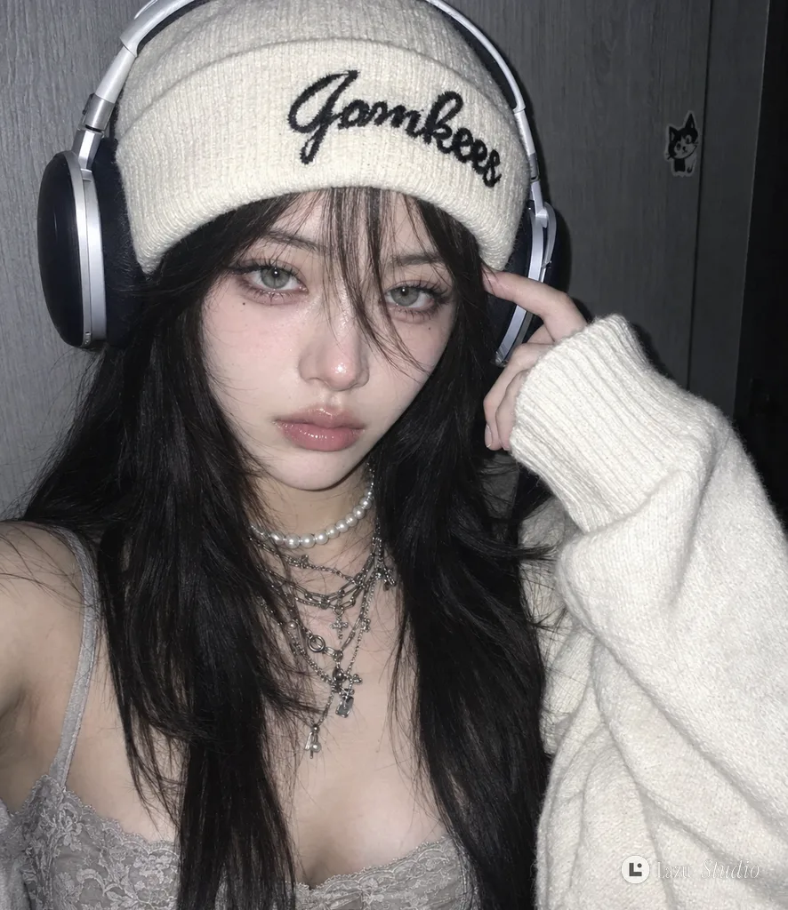 Close-up flash portrait of a young woman in an oversized cream sleeve, beanie, and large over-ear headphones.