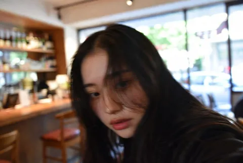 A candid, cropped indoor snapshot of a young Japanese woman at a bar.