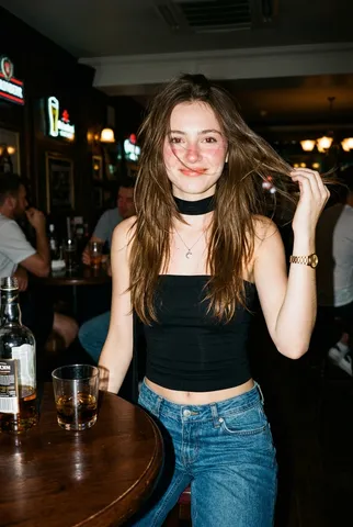Flash photograph of a smiling young woman tossing her hair in a modern pub.
