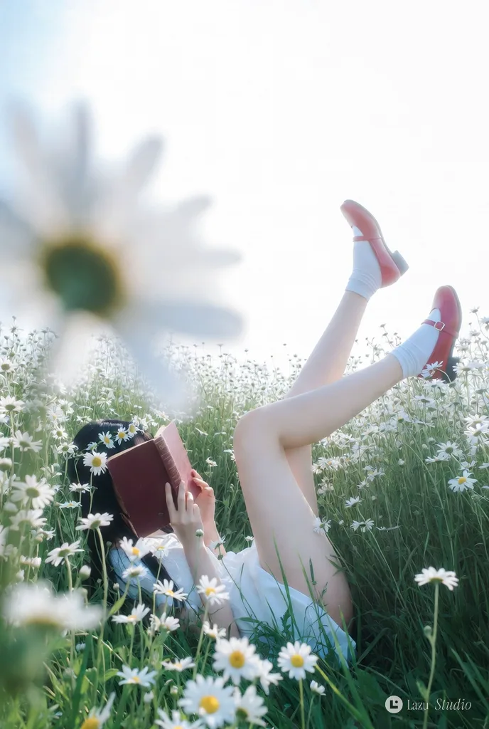 Woman in a white dress lying in a blooming daisy meadow with a book over her face.