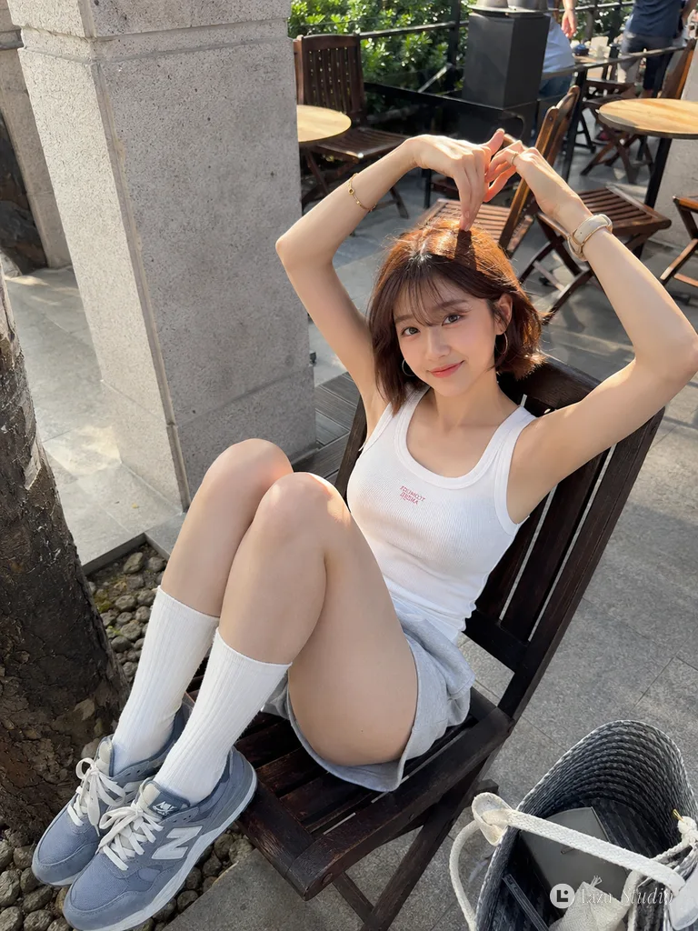 Woman sitting on a chair at a street café making a heart gesture with her hands.