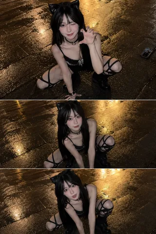 A woman with cat ears and straight dark hair crouching on wet city pavement at night, looking up at the camera.