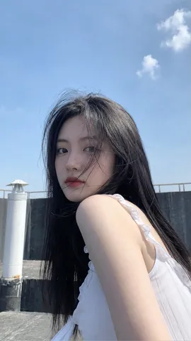 Candid outdoor vertical portrait of a young woman on a rooftop turning her head back toward the camera.